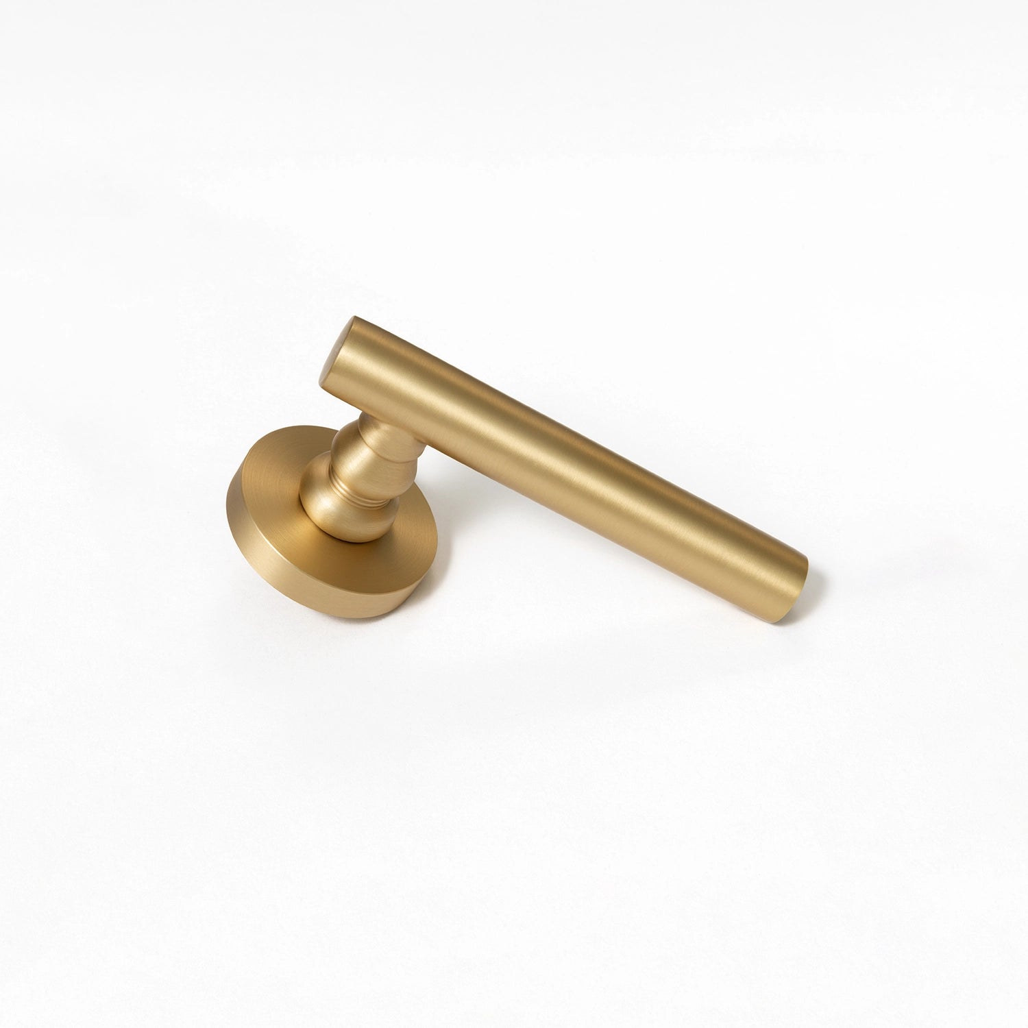 Alda satin brass internal door handle with a round rose, sleek design, positioned vertically standing on its base.