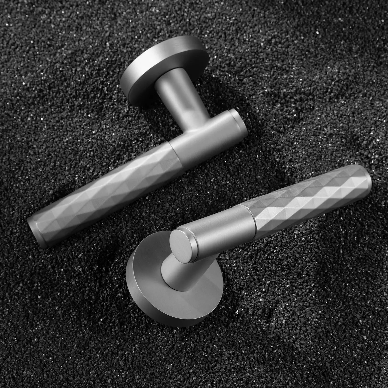 Two Fendal-01 internal door handles in nickel finish with diamond pattern grip, displayed on a textured stone background.