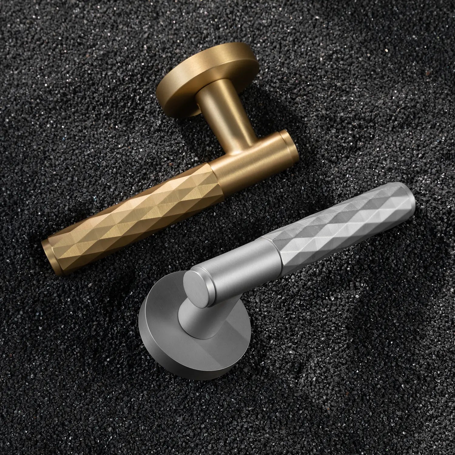 Two Fendal-01 door handles in satin brass and nickel finishes with diamond pattern grips, displayed on a textured stone background.