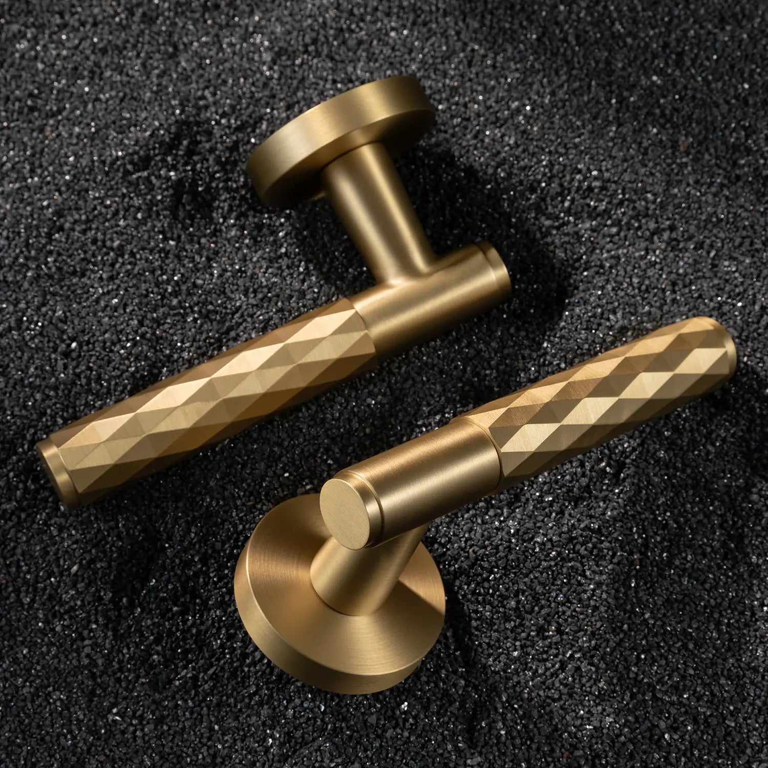 Two Fendal-01 internal door handles in satin brass finish with diamond pattern grip, displayed on a textured stone background.
