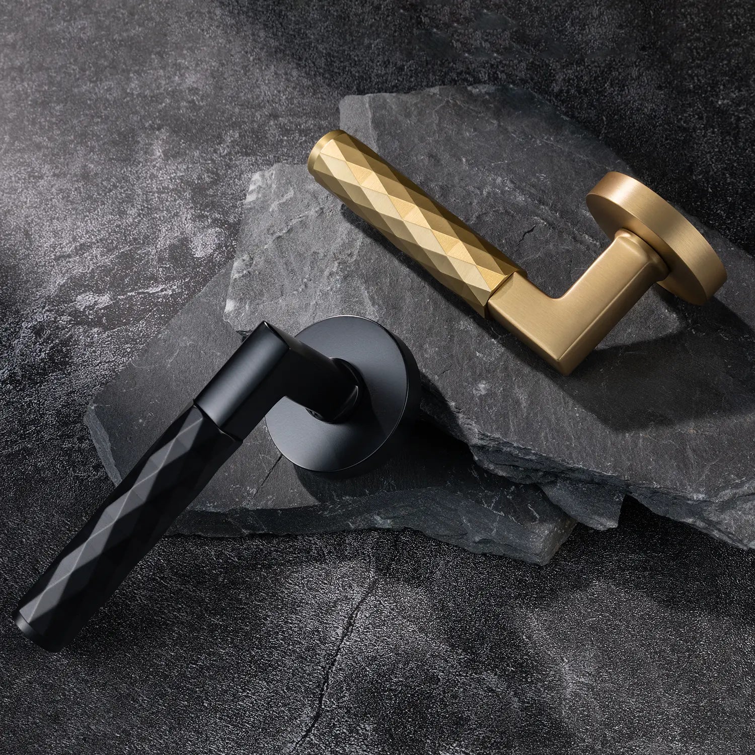 Two Fendal-02 door handles in satin brass and black finishes with diamond pattern grips, displayed on a textured stone background.