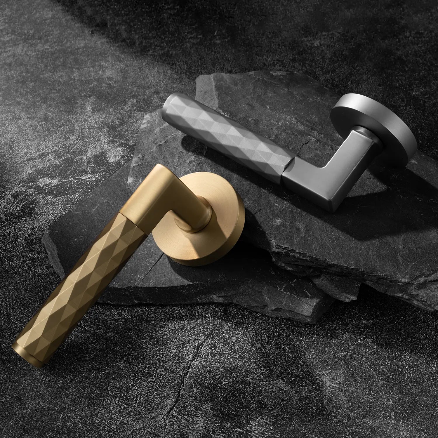 Two Fendal-02 door handles in satin brass and nickel finishes with diamond pattern grips, displayed on a textured stone background.