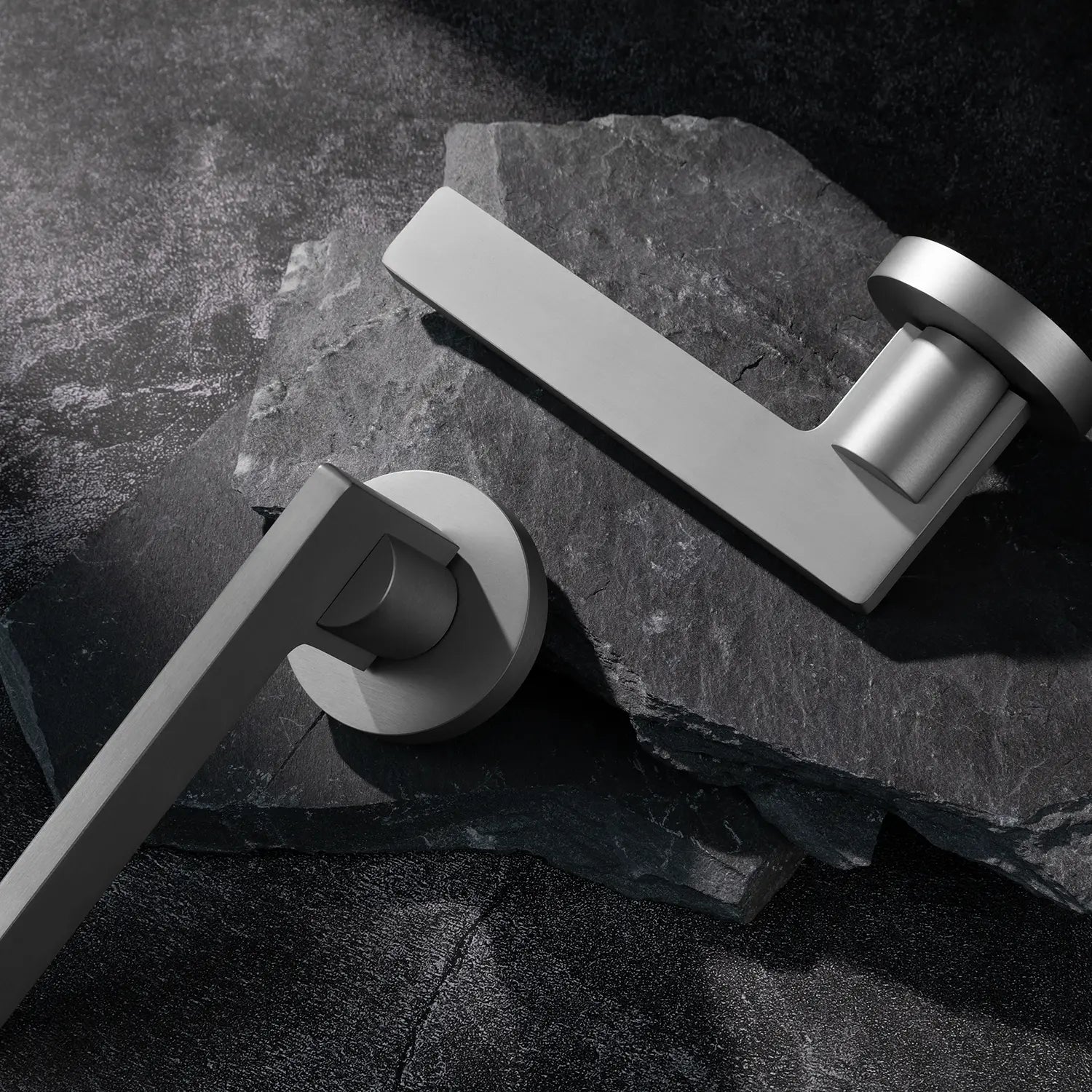 Two Filda door handles in nickel finish, displayed on a textured stone background.