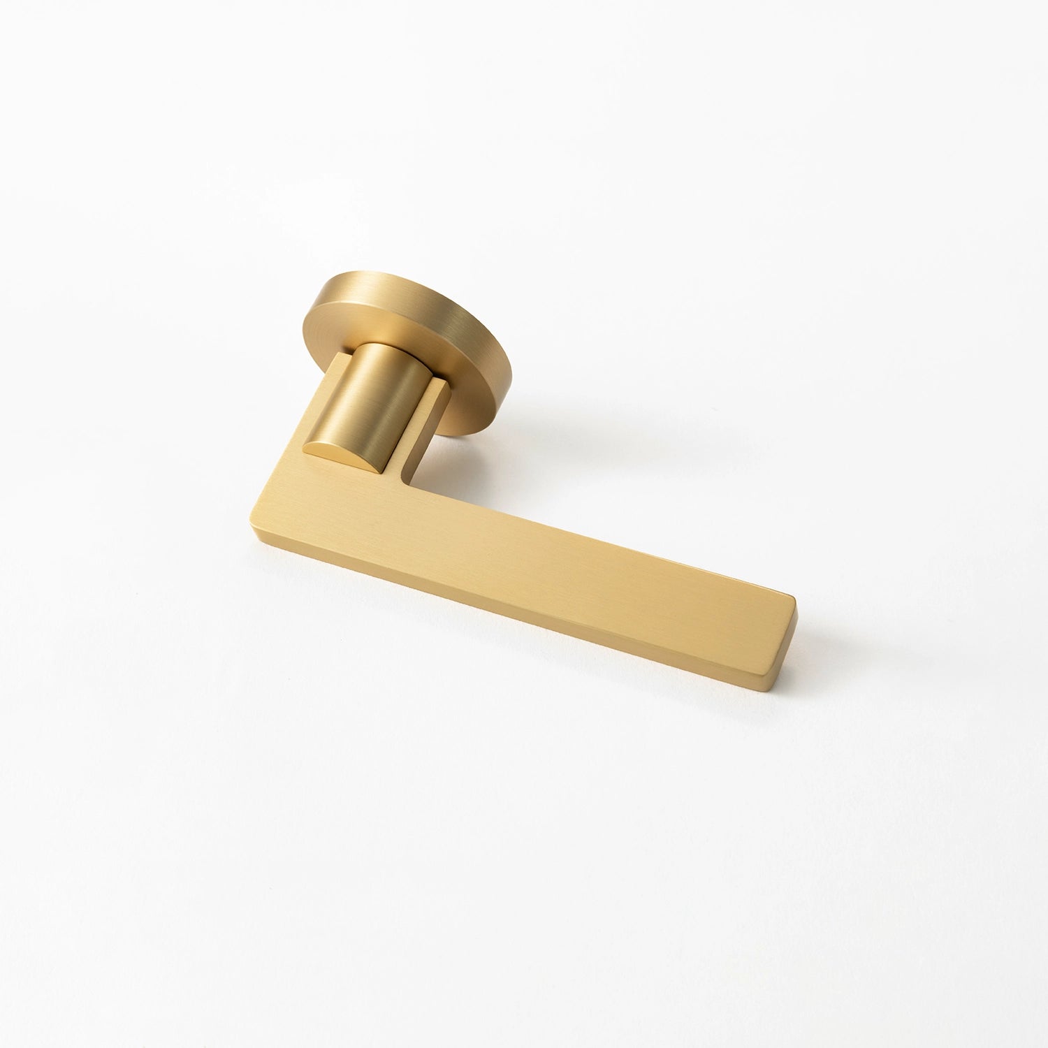 Filda satin brass internal door handle with a round rose, positioned horizontally on a flat surface.