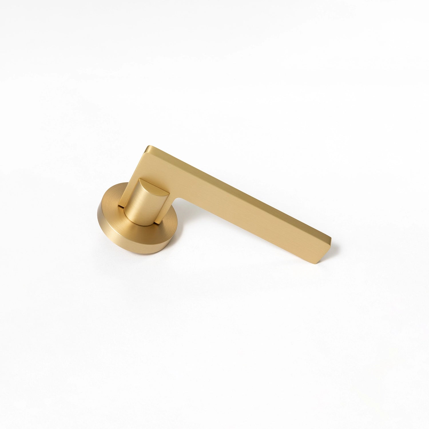 Filda satin brass internal door handle with a round rose, positioned vertically standing on its base.