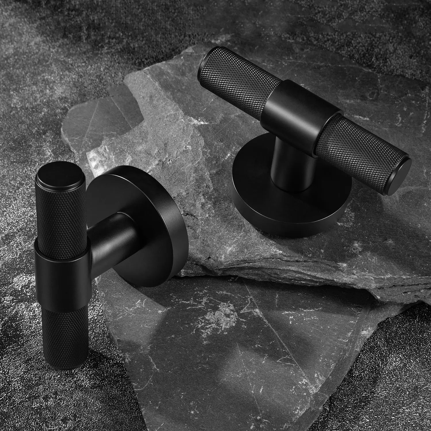 Two Heik internal door handles in matte black finish, placed on a dark textured stone background.
