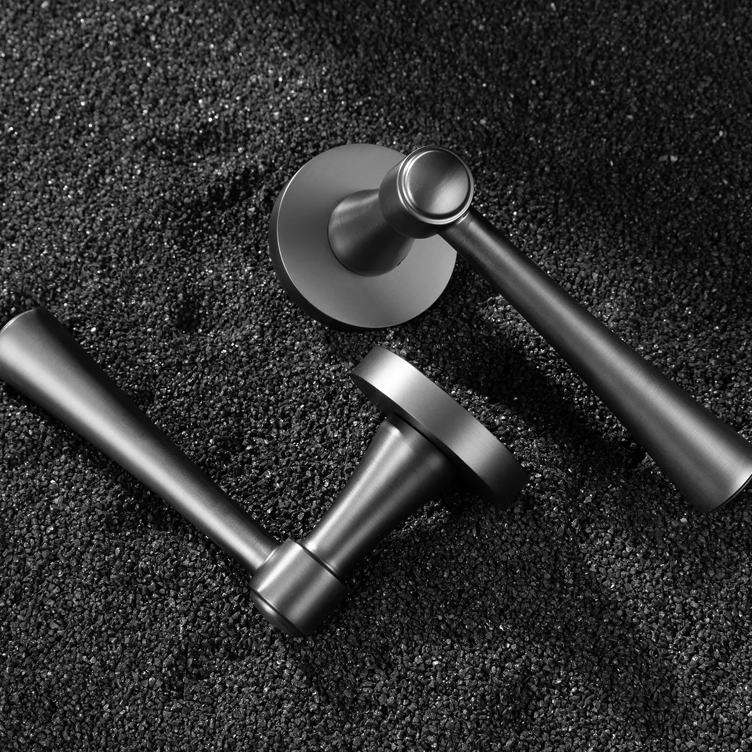 Two Hilda door handles in charcoal grey finish, elegantly positioned on a textured black surface. Featuring sleek and timeless cone-shaped design for modern interiors.