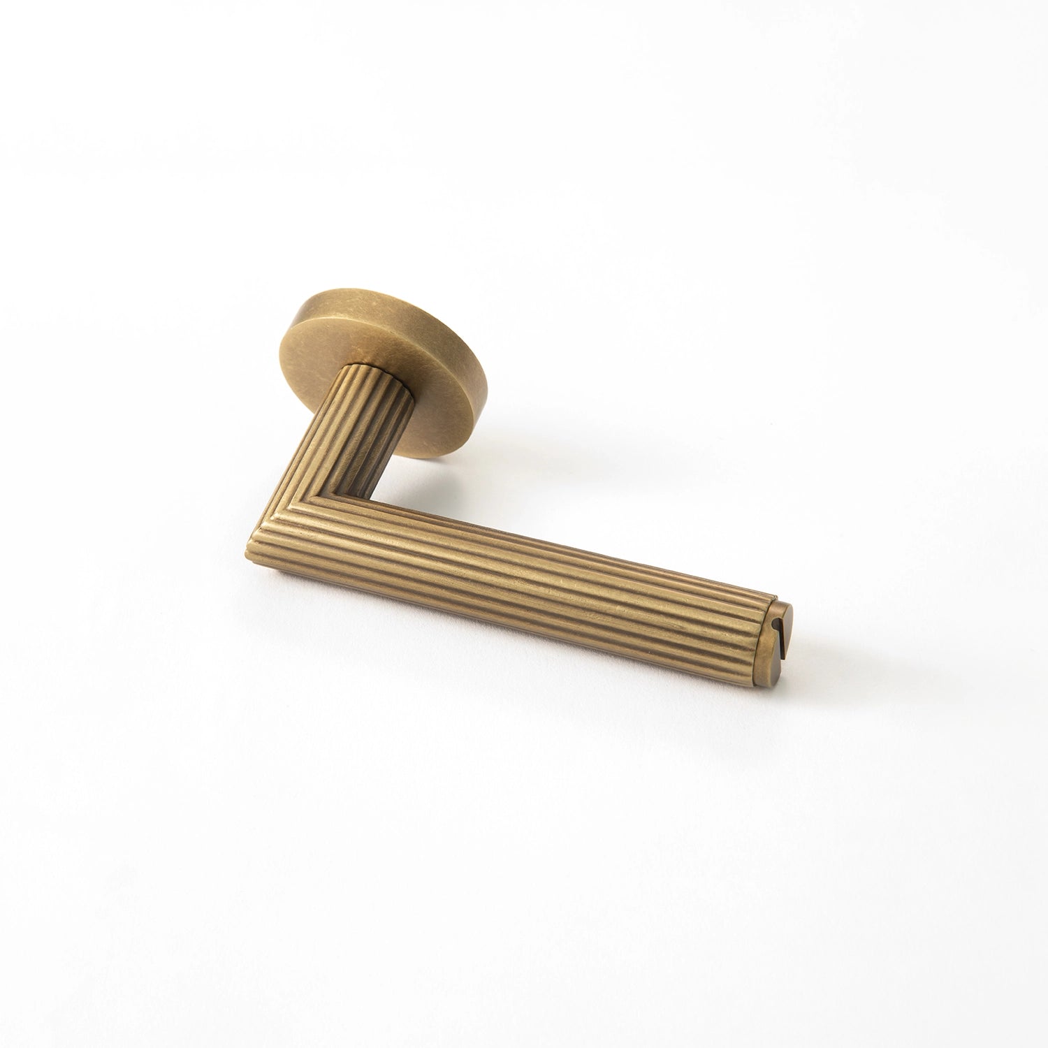 Midal door handle in ochre antique brass finish, positioned horizontally on a flat surface, showcasing a distinctive linear pattern for an elegant touch.