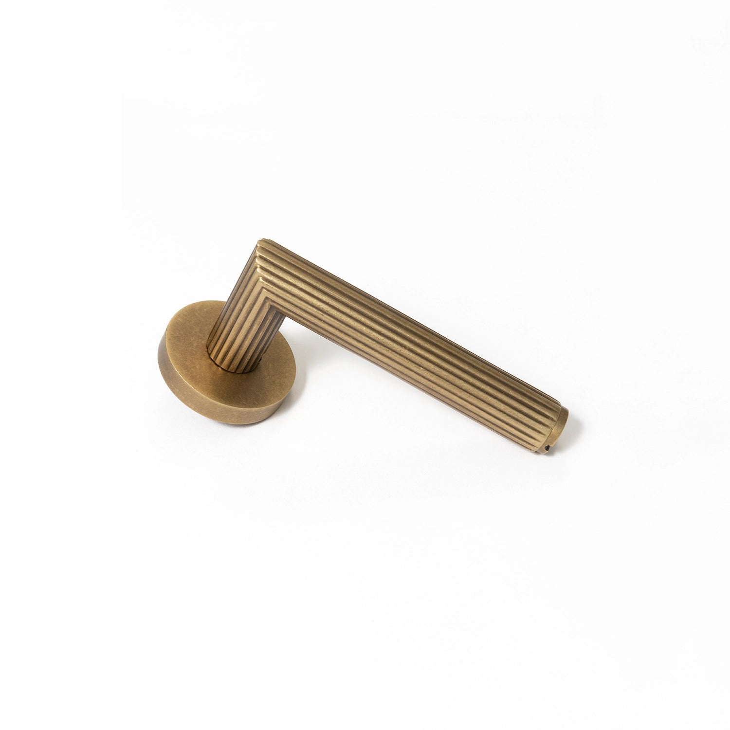 Midal door handle in ochre antique brass finish, positioned vertically standing on its base, showcasing a distinctive linear pattern for an elegant touch.