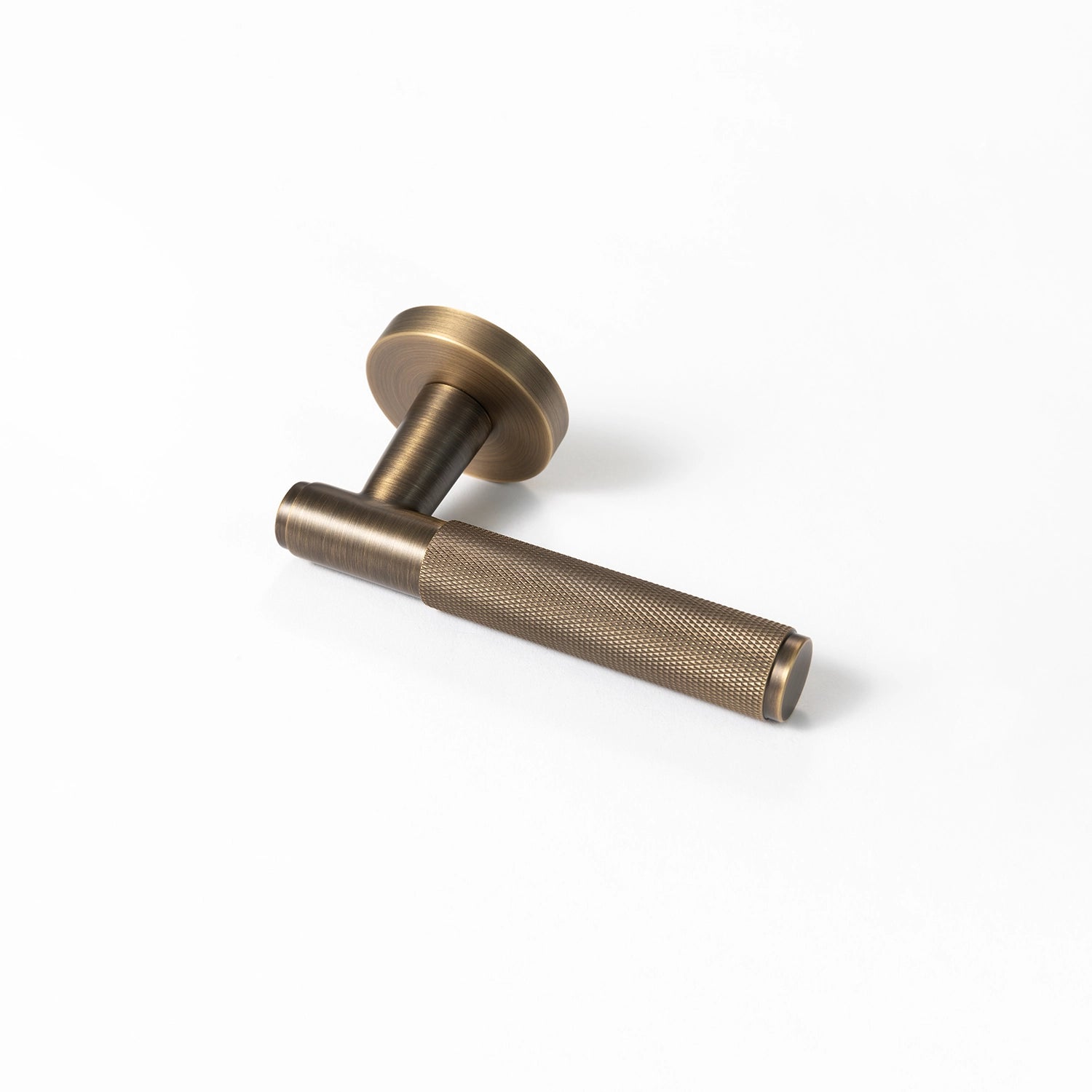 Svik-01 door handle in antique brass finish, featuring an extended knurled pattern grip for a modern industrial aesthetic. Positioned horizontally on a plain white background to highlight its intricate texture.