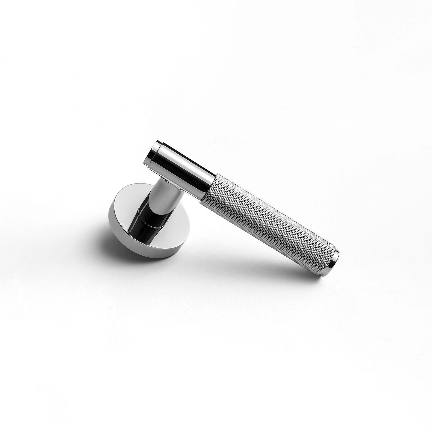 Svik-01 polished chrome door handle with knurled pattern, standing vertically on a flat surface, showcasing its industrial aesthetic.