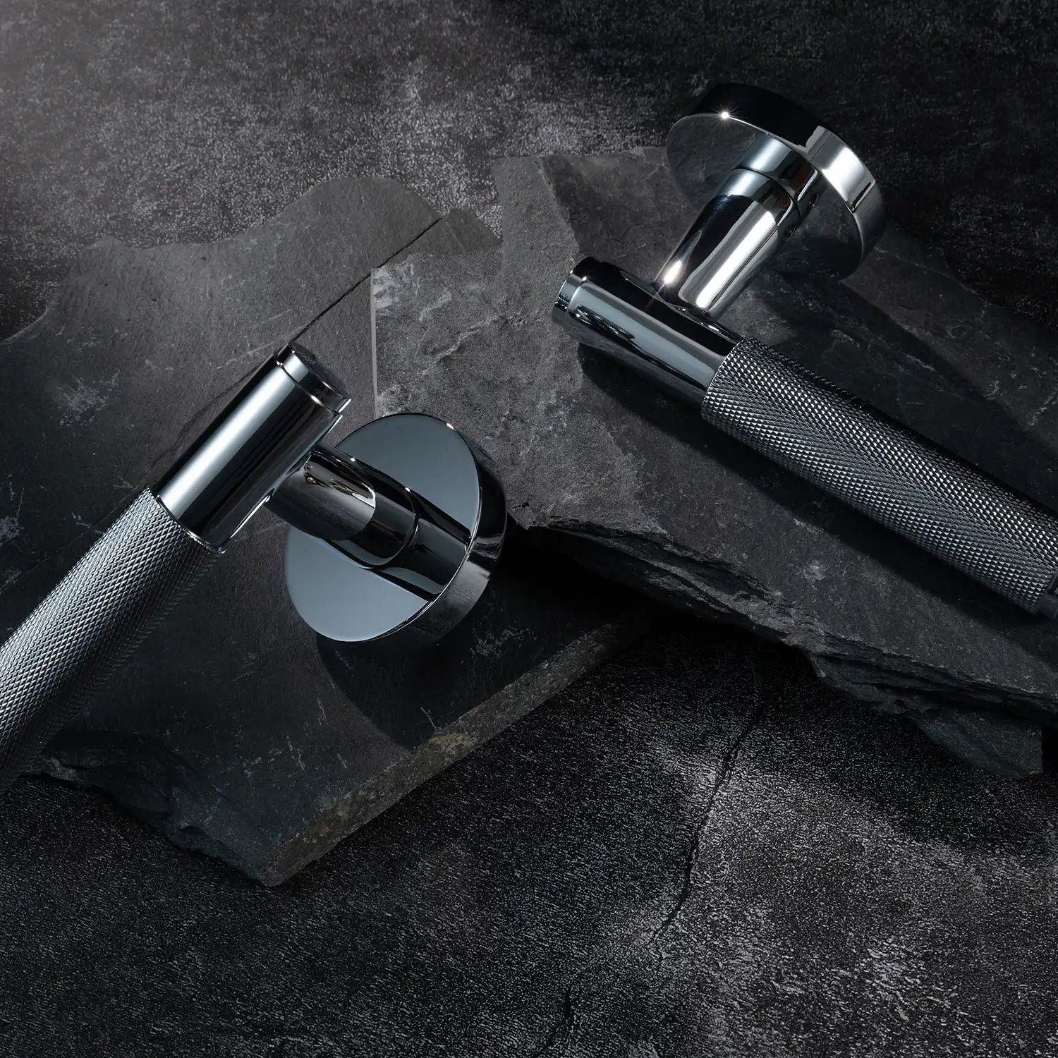Two Svik-01 internal door handles with knurled pattern, polished chrome finish, displayed on a layered slate stone background.