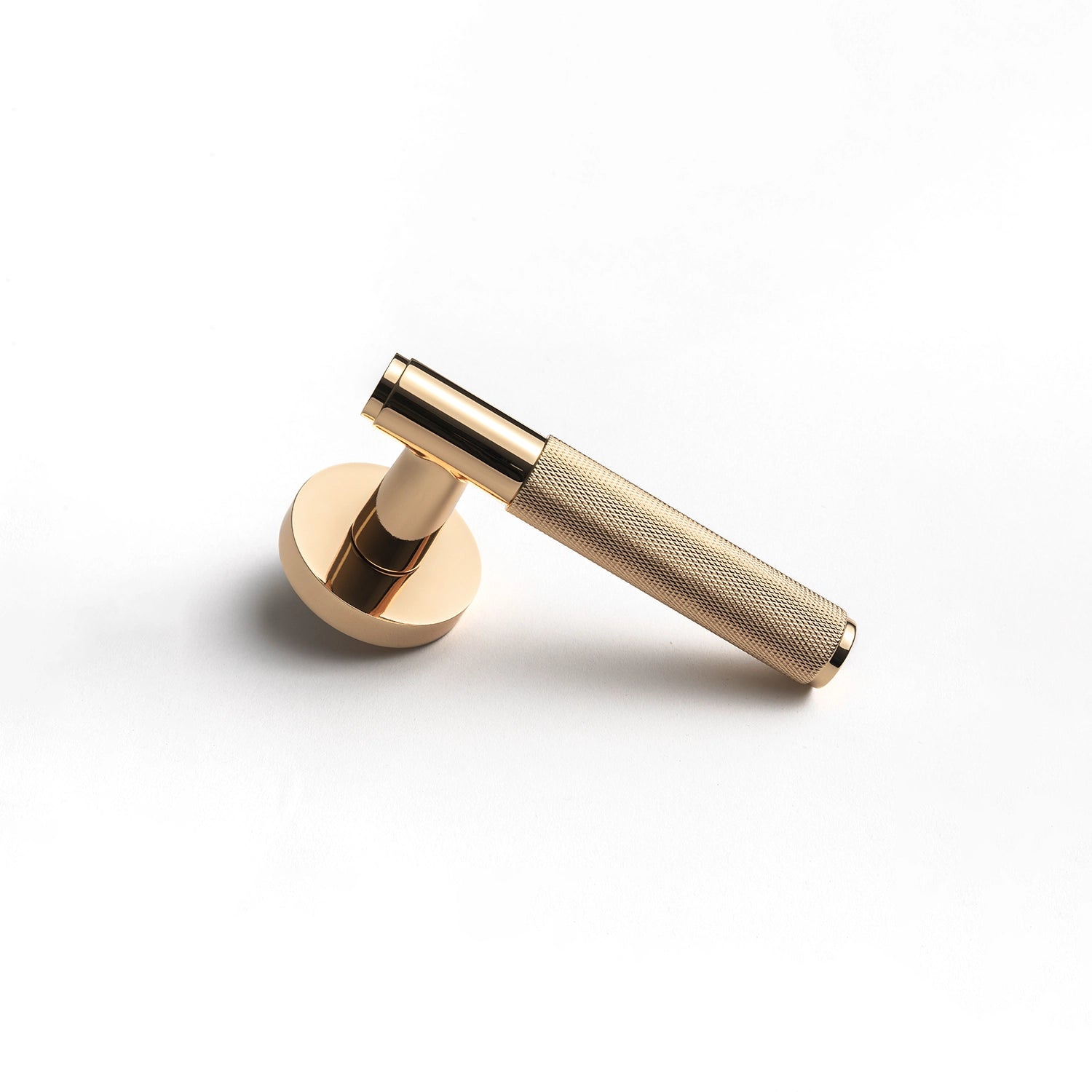 Svik-01 polished gold door handle with knurled pattern, standing vertically on a flat surface, showcasing its industrial aesthetic.