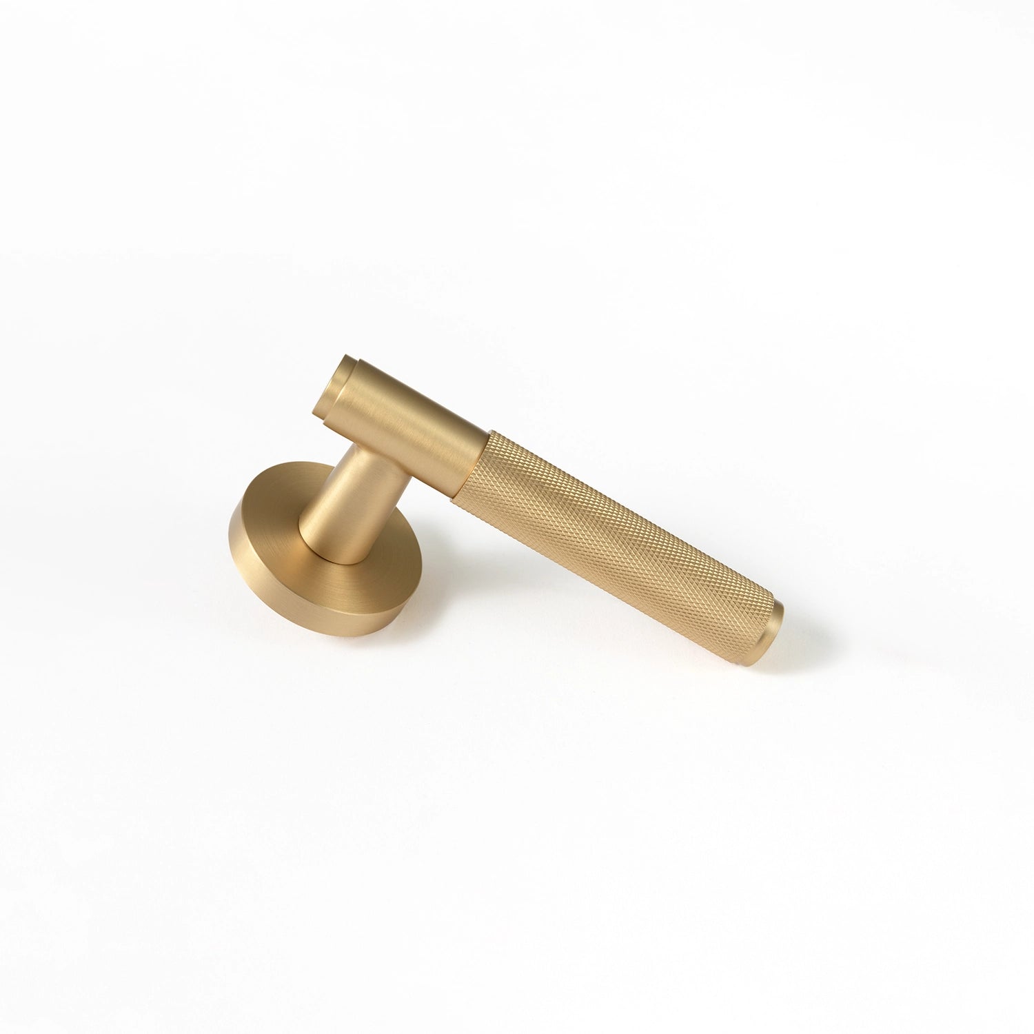 Svik-01 satin brass door handle with knurled pattern, standing vertically on a flat surface, showcasing its industrial aesthetic.
