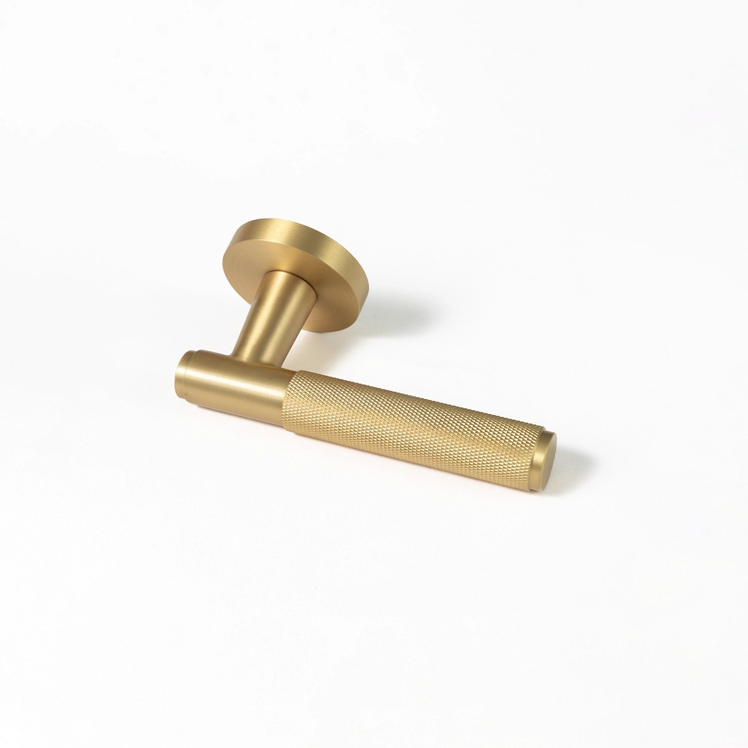 Svik-01 door handle in satin brass finish, featuring an extended knurled pattern grip for a modern industrial aesthetic. Positioned horizontally on a plain white background to highlight its intricate texture.