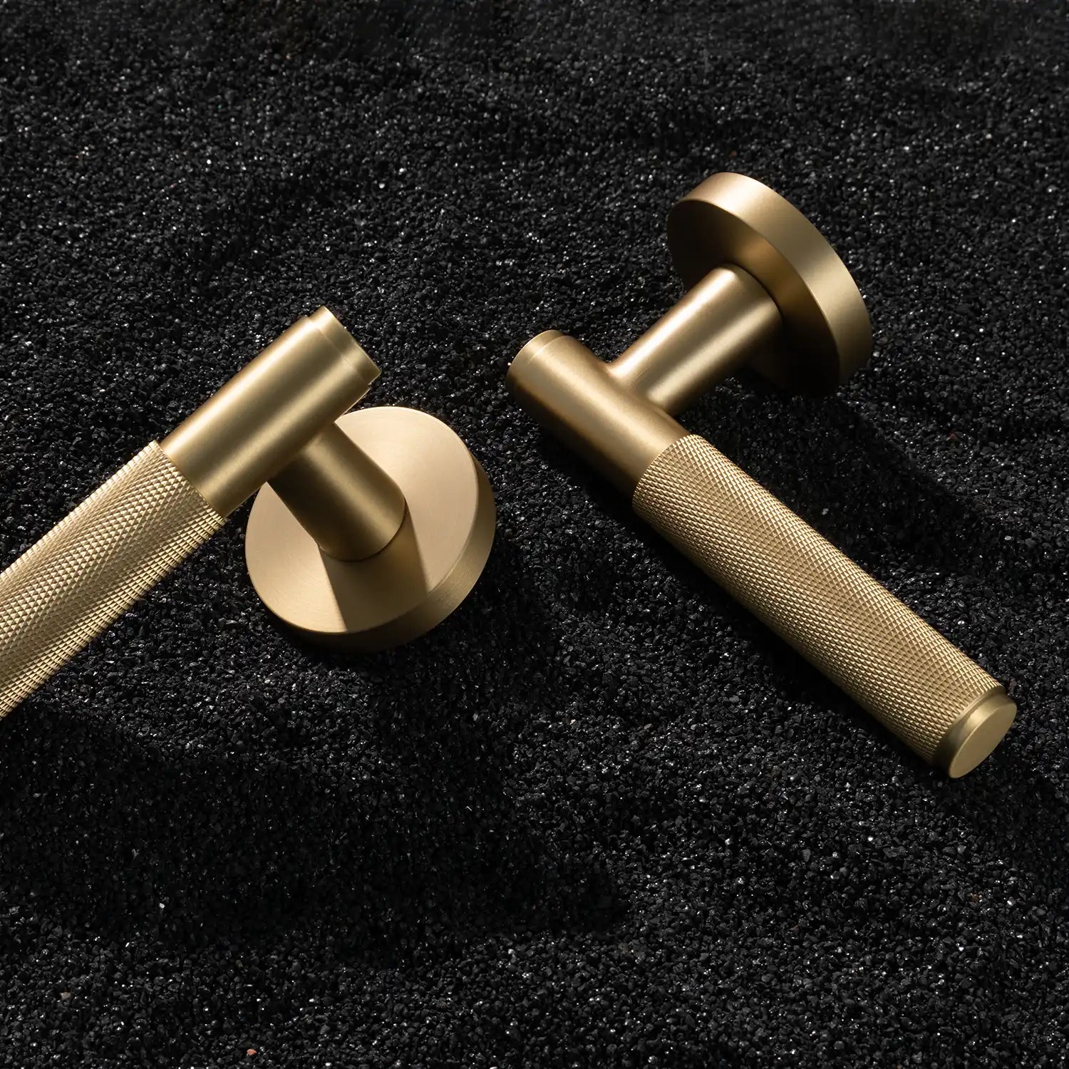 Svik-01 internal door handle with knurled pattern in satin brass finish, displayed horizontally on a textured gravel background.