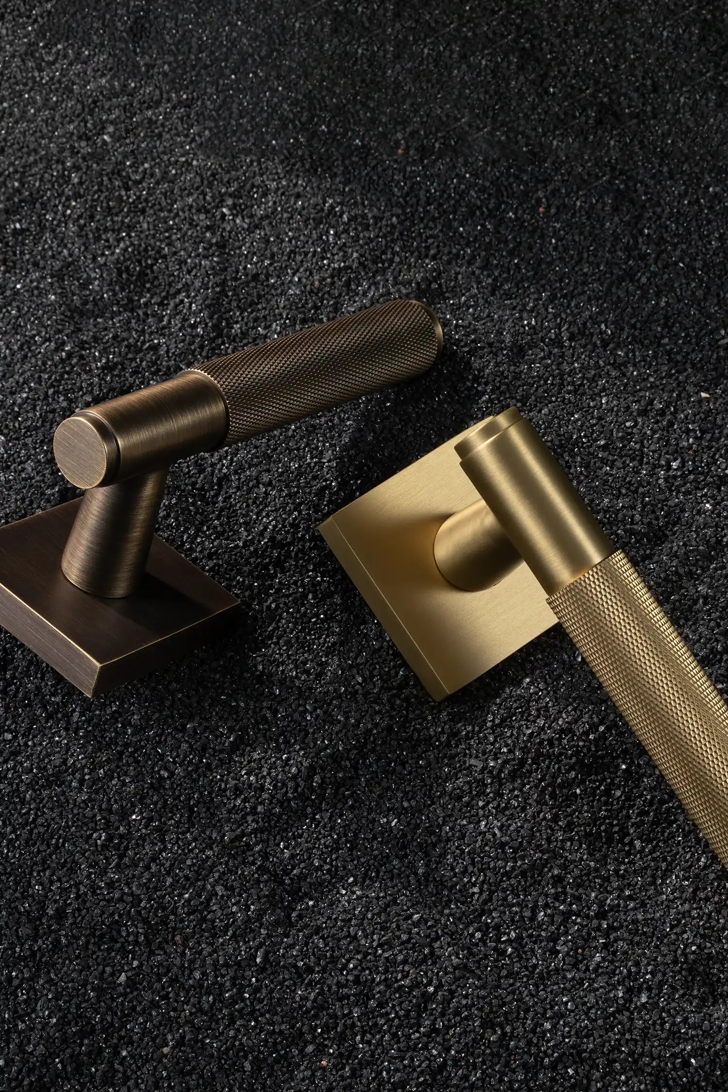 Svik-01 internal door handles in satin brass and antique brass finishes, featuring knurled pattern grips, paired with square rose bases, displayed on a textured black gravel background.