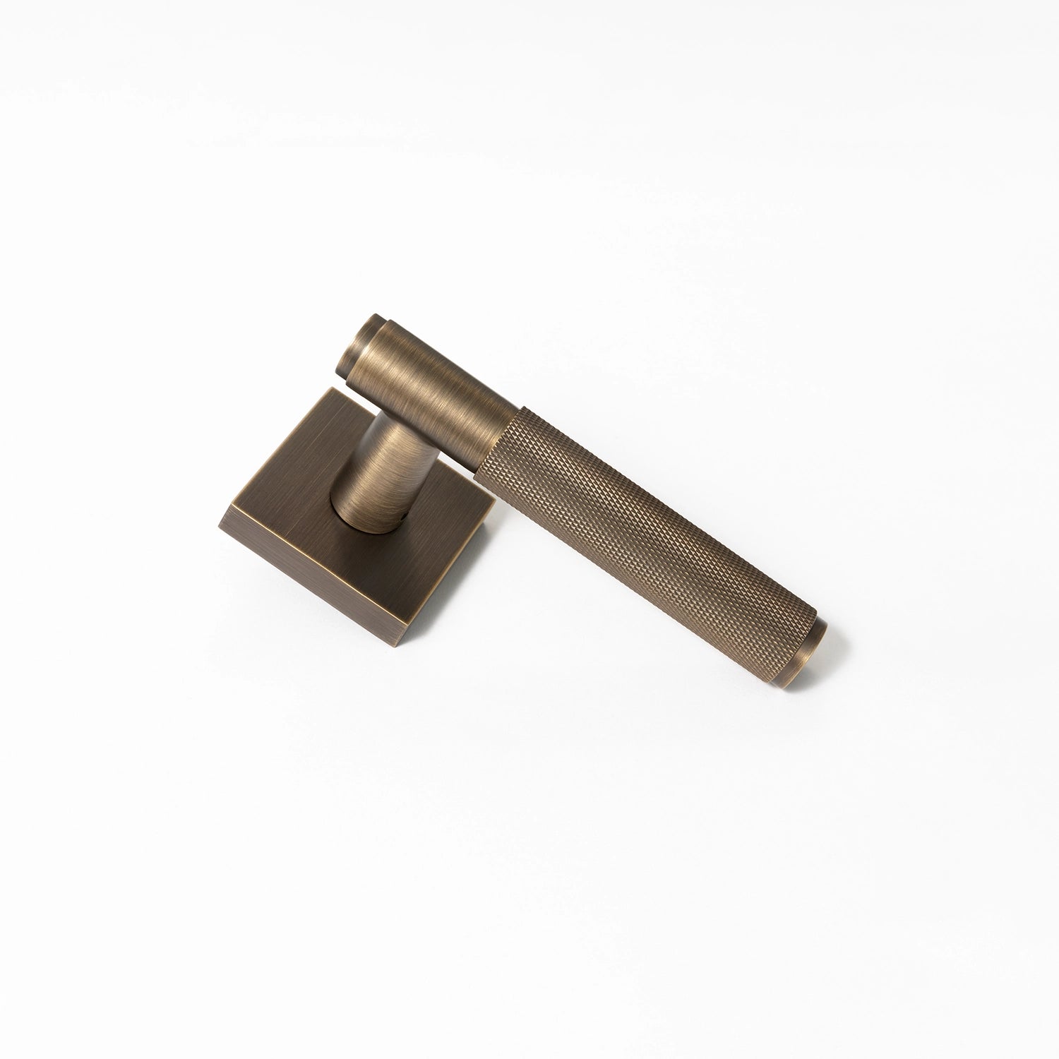 Svik-01 internal door handle in antique brass finish with knurled pattern grip, standing upright on a square rose base.