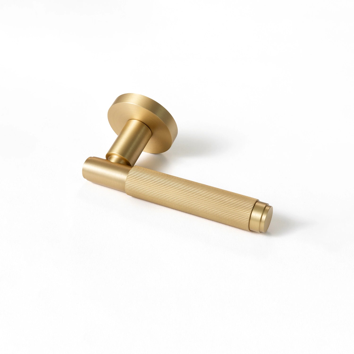 Svik-02 internal door handle in satin brass finish, positioned horizontally on a flat surface, showcasing a linear pattern on the gripping section.