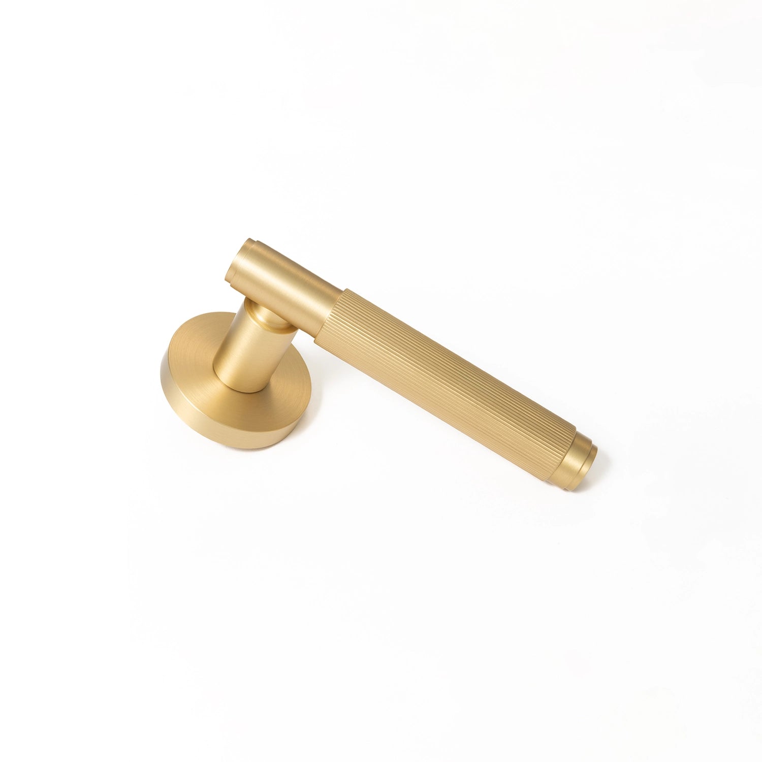 Svik-02 internal door handle in satin brass finish, lying diagonally with a round rose base, featuring a distinct linear pattern on the handle.