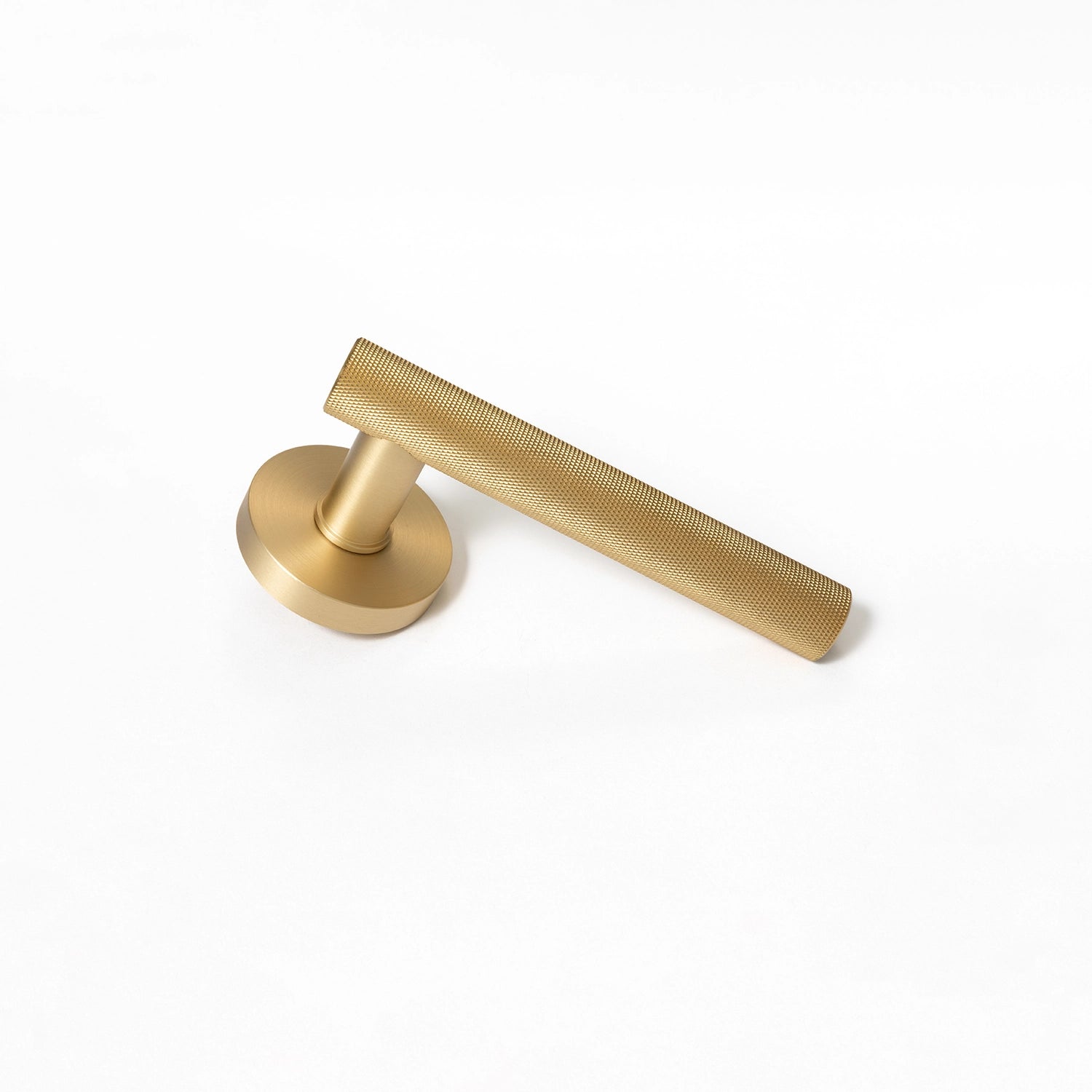 Tord-01 internal door handle in satin brass finish, featuring a fully knurled pattern covering the entire handle, placed diagonally on a white background.