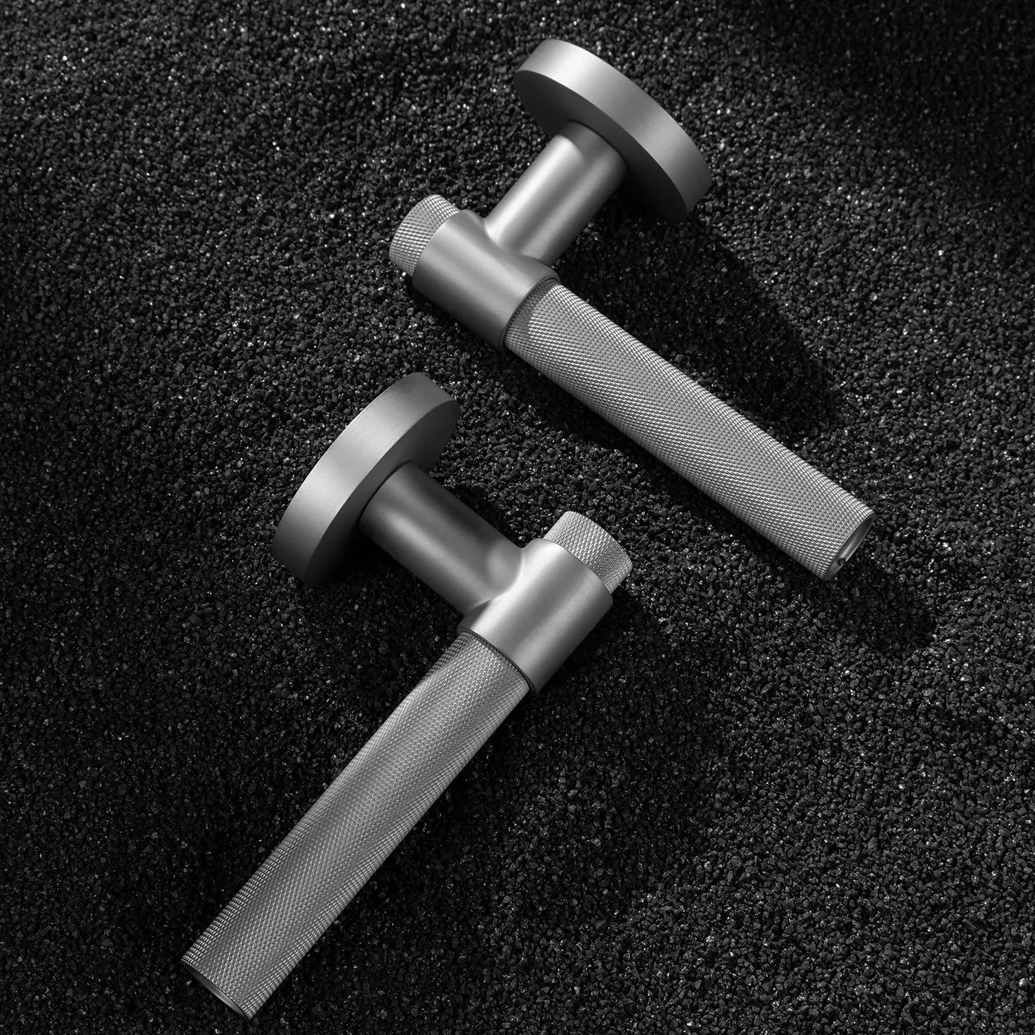 Two Tord-02 internal door handles in nickel finish, featuring a large area of knurled pattern on the grip, displayed on a textured gravel background.