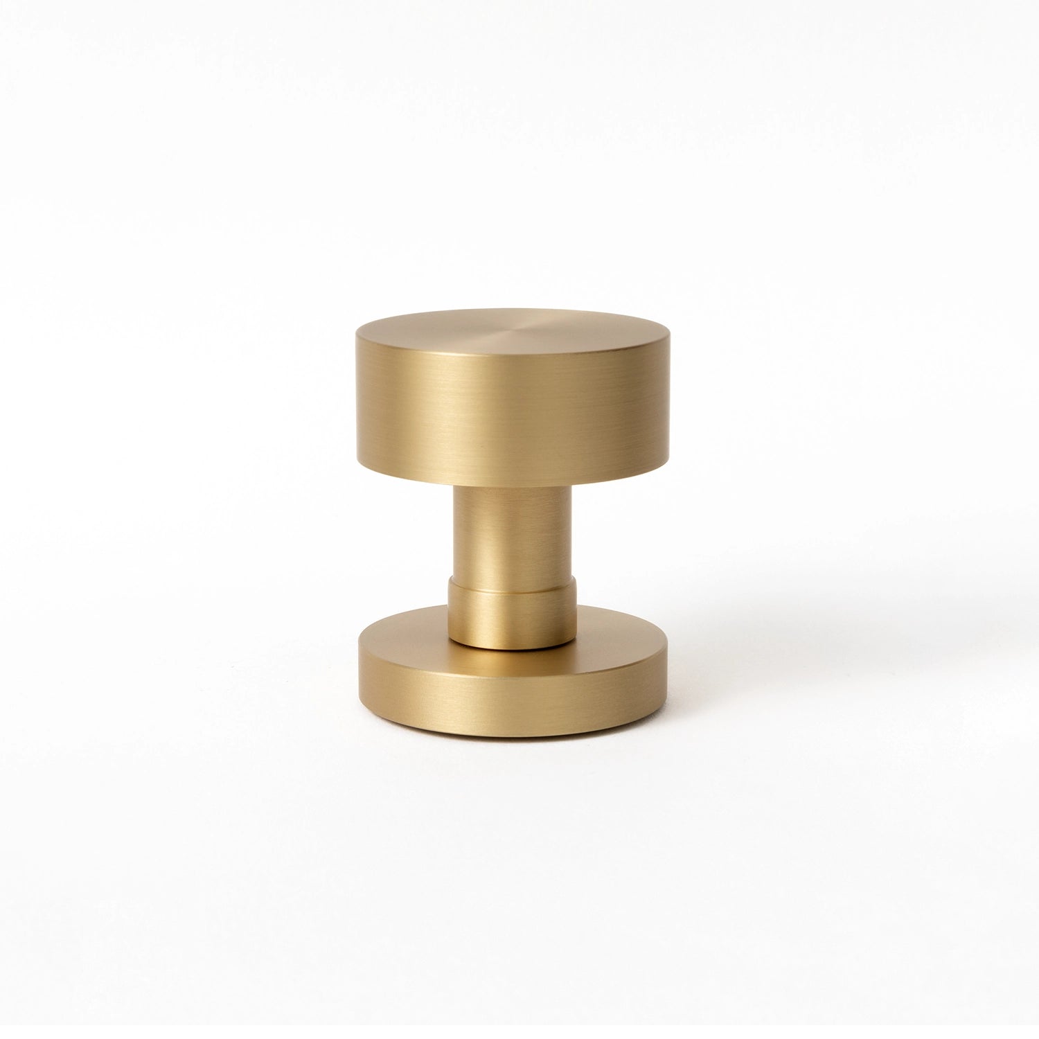 Solda door knob in satin brass finish, showcased upright on a white background, highlighting its cylindrical and modern design.