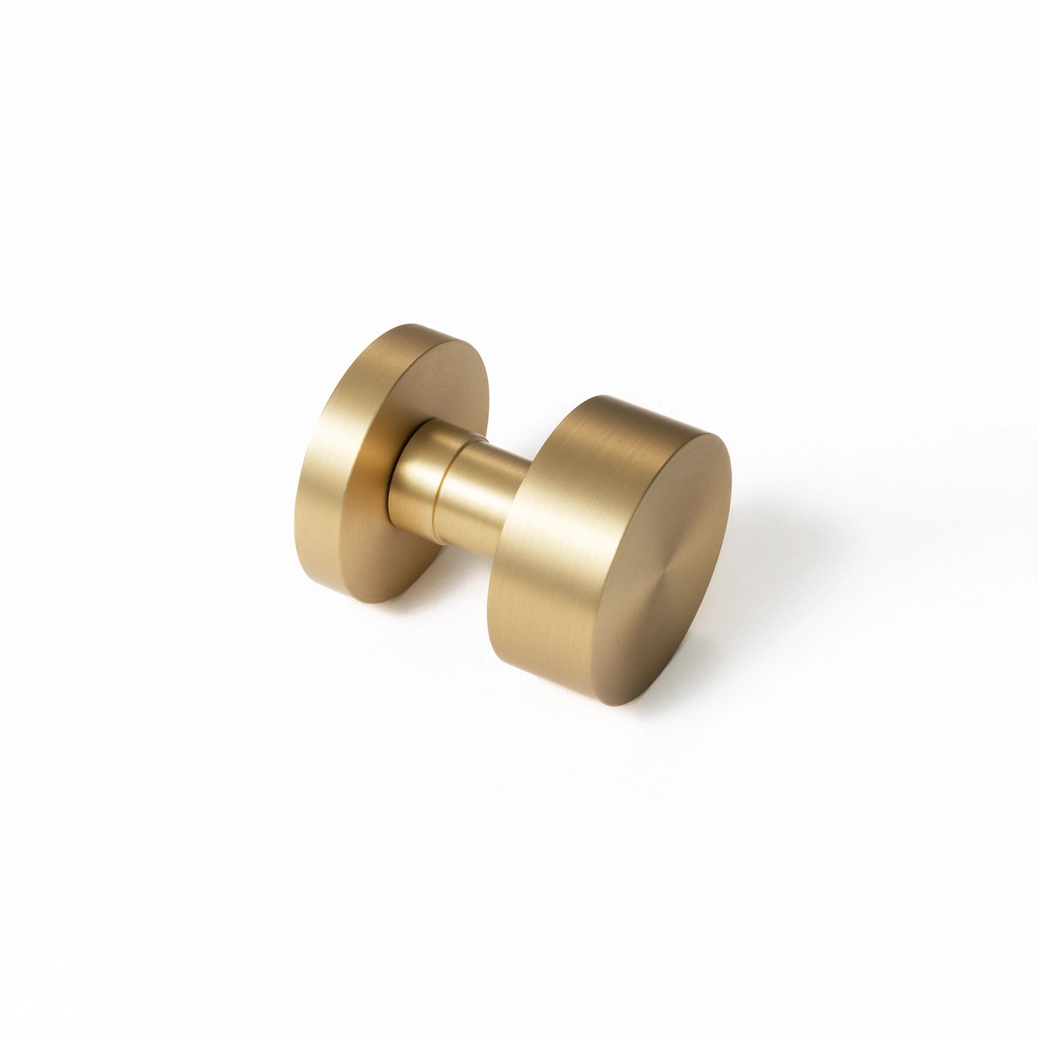 Solda round door knob in satin brass finish, positioned at an angle on a white background, showcasing its minimalist and modern design.