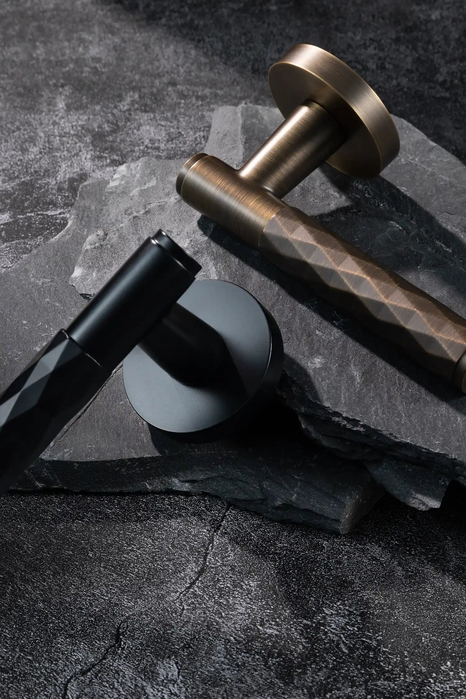 Fendal01 door handles in antique brass and black finishes with diamond pattern grips, displayed on a textured stone background. A modern and versatile design for contemporary interiors.