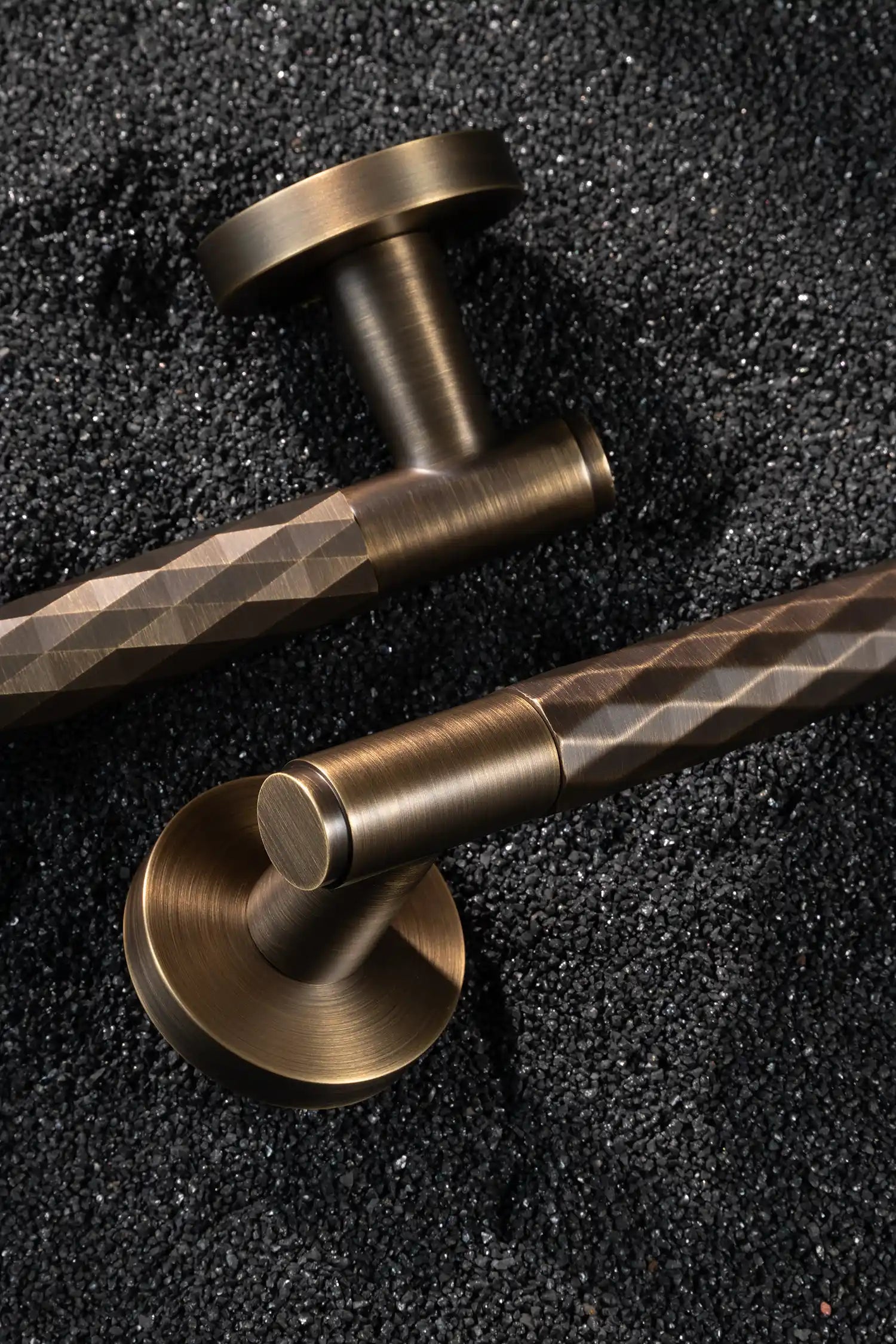 Fendal01 Internal door handles in antique brass finish with diamond pattern grip, displayed on a textured stone background. Elegant and modern design for contemporary interiors.