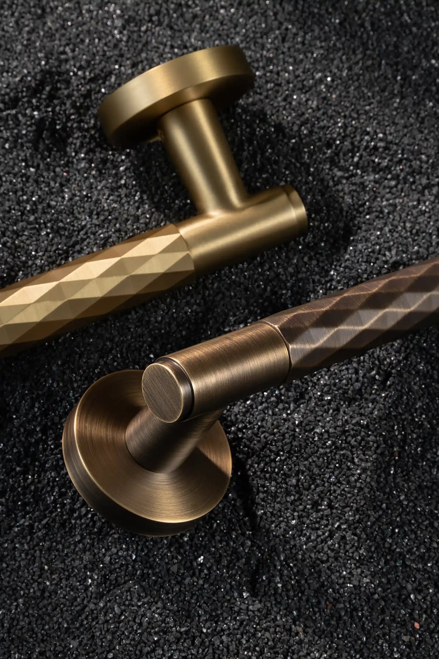 Fendal01 door handles in satin brass and antique brass finishes with diamond pattern grips, displayed on a textured stone background. A modern and versatile design for contemporary interiors.