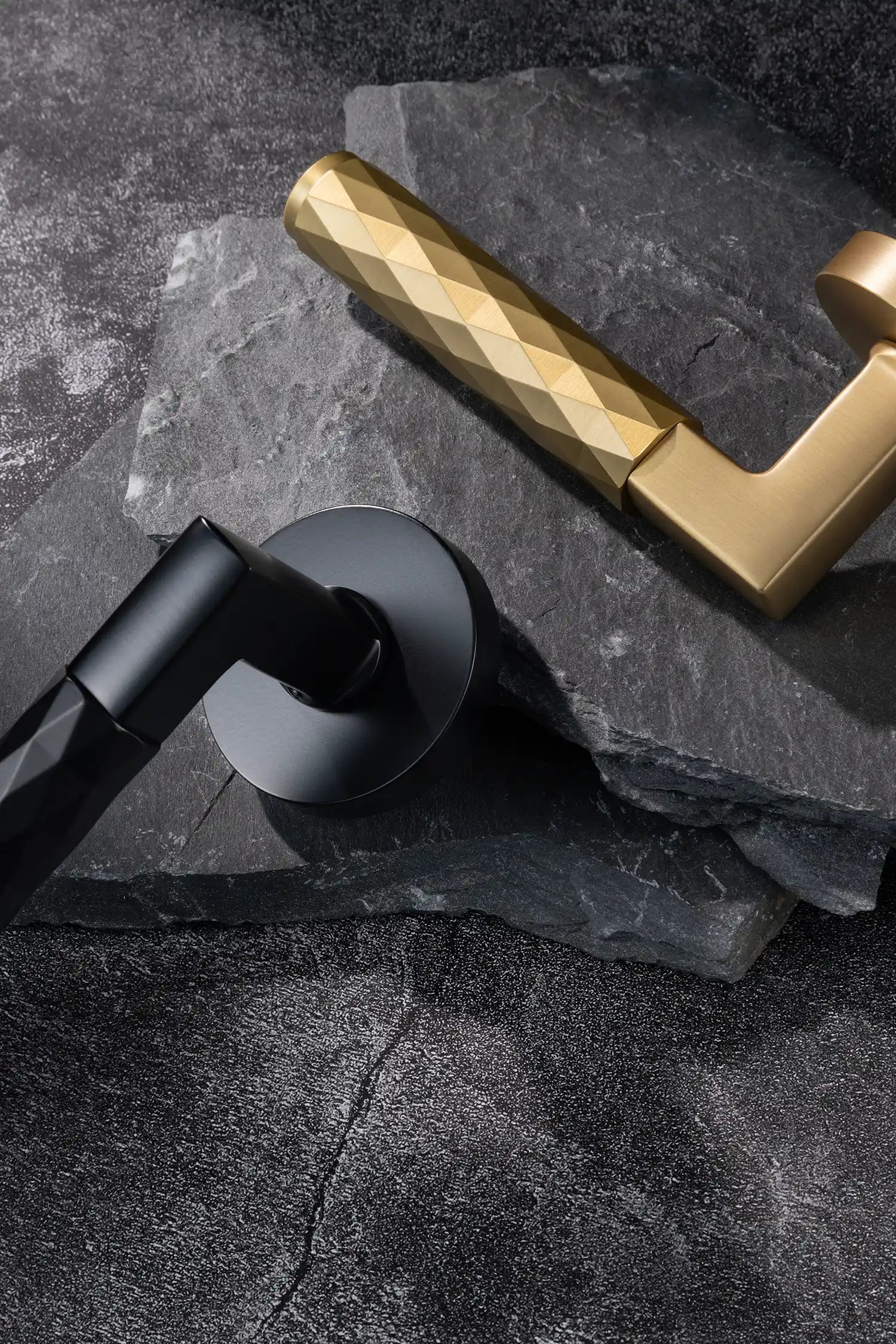 Fendal02 door handles in satin brass and black finishes with diamond pattern grips, displayed on a textured stone background. A modern and versatile design for contemporary interiors.