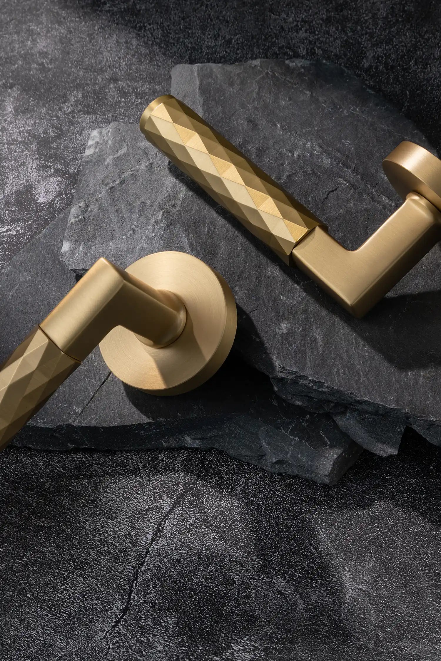 Internal Fendal02 satin brass door handles with diamond pattern grip, showcased on a textured stone background. Elegant and modern design for contemporary interiors.