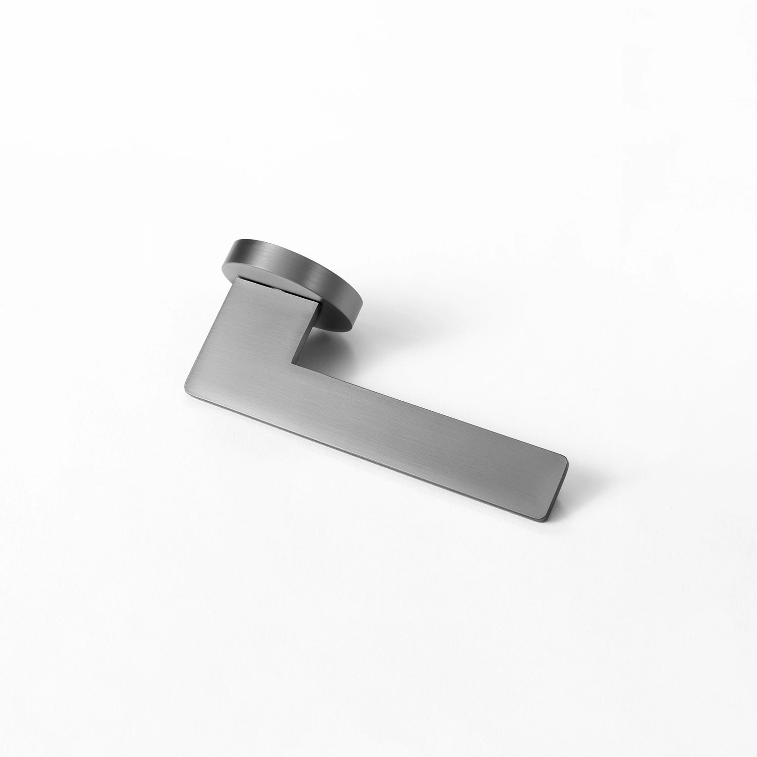 Tagg internal door handle in charcoal grey finish, showcasing a minimalist round rose design and sleek geometric lever, positioned horizontally on a white background.